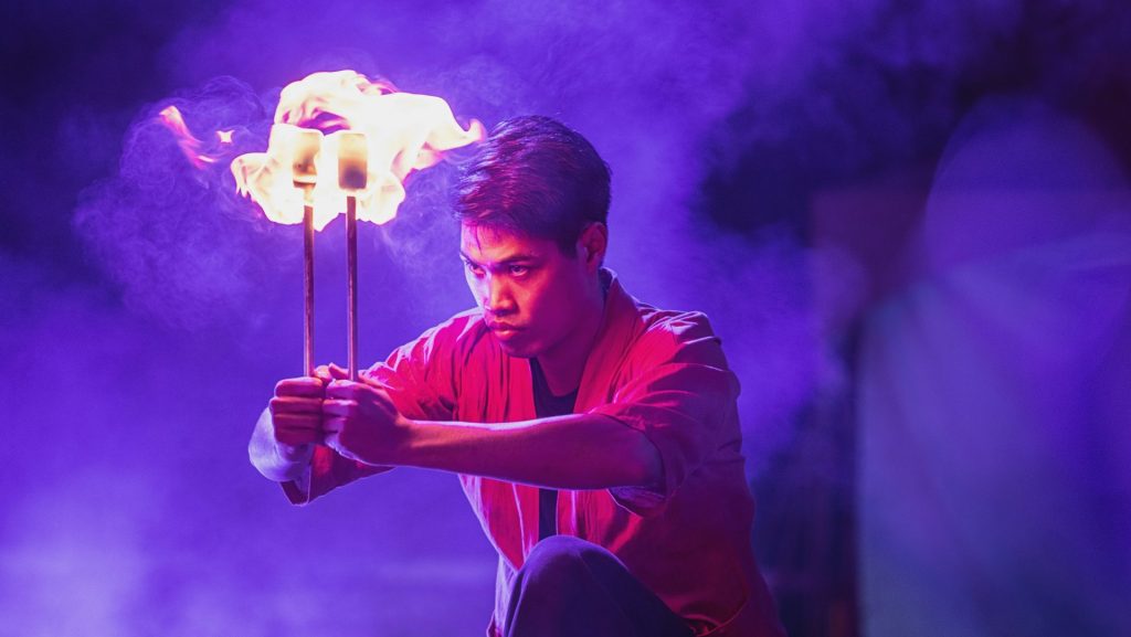 A man holding a stick in front of a purple light